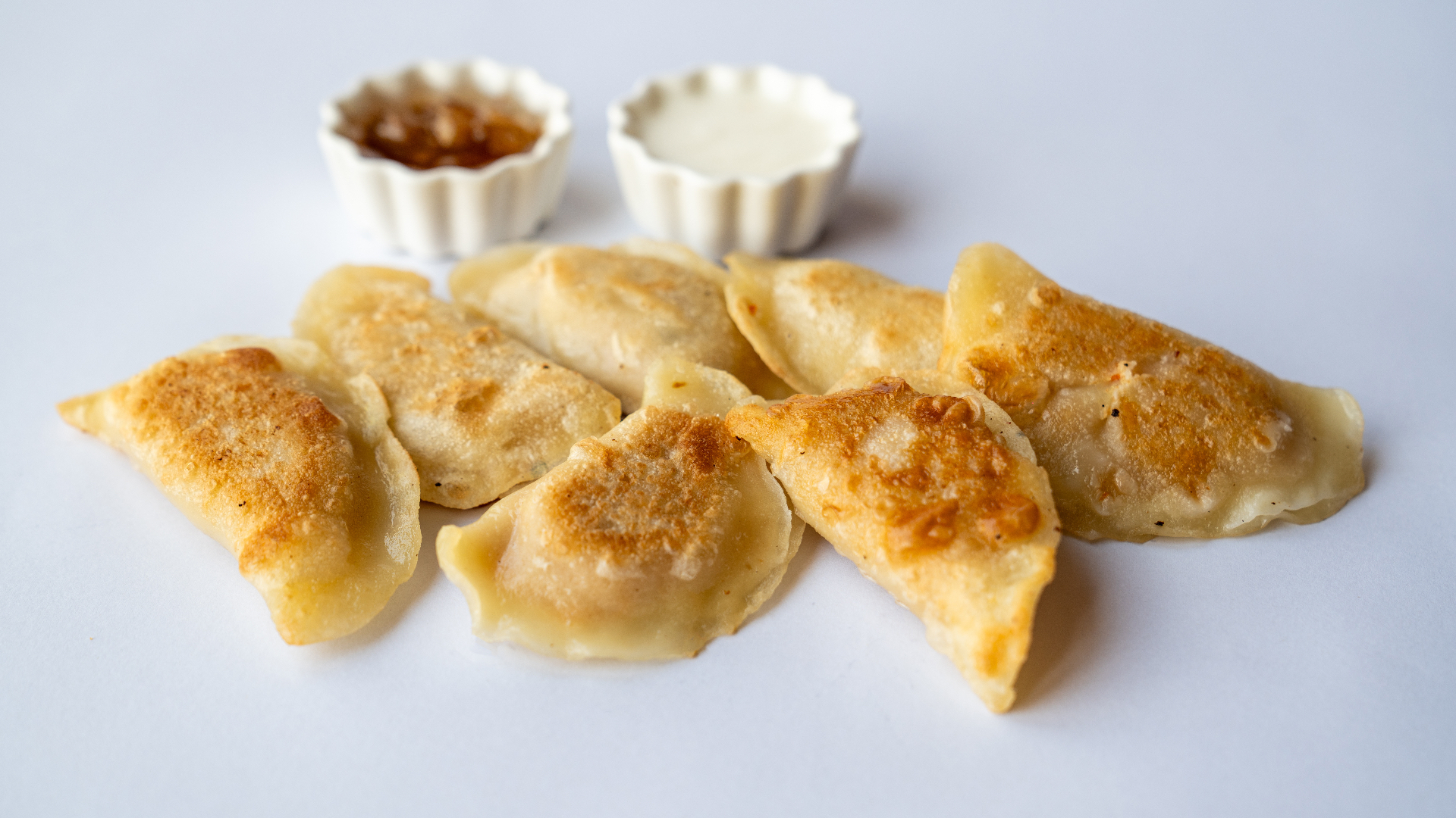 Golden pan-fried pierogi with dipping sauces